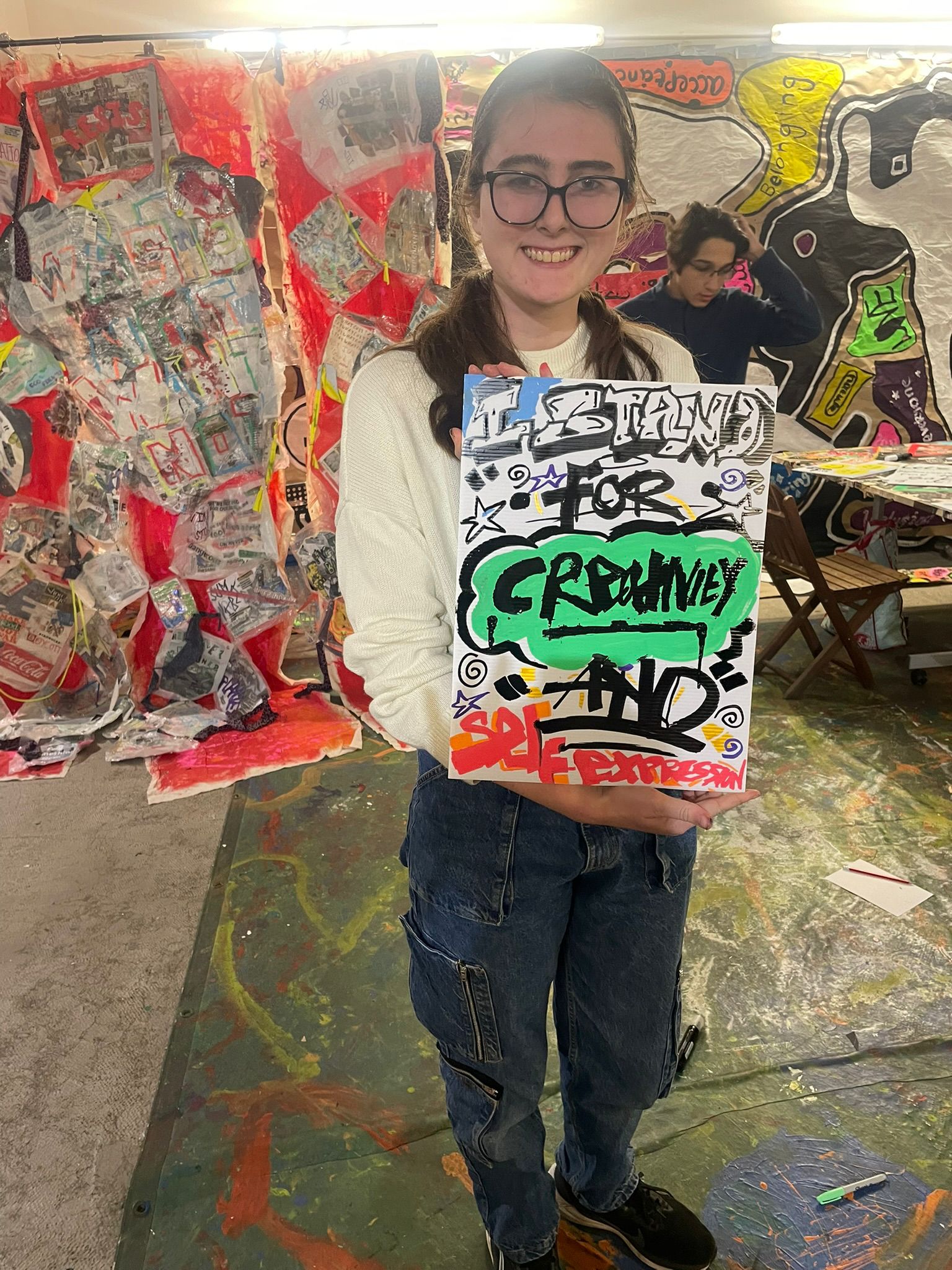 Young participant holding artwork about creativity and self-expression during an England youth session